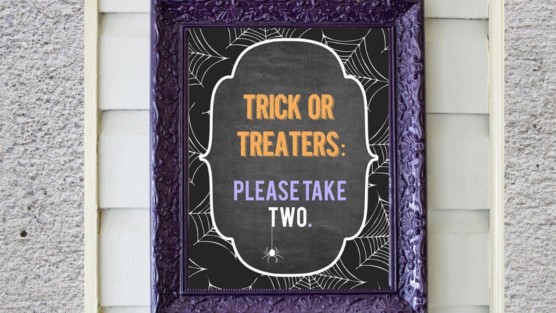 May include: A black chalkboard sign with a white frame and a spiderweb design. The sign says "Trick or Treaters: Please Take Two."