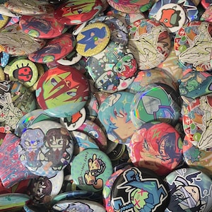 Può includere: Una collezione di bottoni rotondi e colorati con vari disegni. I bottoni presentano illustrazioni di personaggi anime, arte astratta e personaggi dei cartoni animati. Alcuni bottoni hanno effetti olografici e il testo "Funky Tunes 4" è visibile.