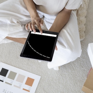 Könnte beinhalten: Ein schwarzes Tablet zeigt eine weiße gestrichelte Linie auf einem schwarzen Bildschirm. Eine Farbpalette mit schwarzen, grauen und beigen Farbfeldern ist sichtbar. Eine weiße Box mit Gebäck und eine braune Box sind ebenfalls im Bild.