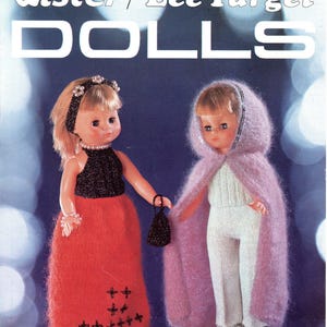 May include: A vintage knitting pattern booklet titled Lister/Lee Target DOLLS 557. The cover features two dolls: one in a black halter top and red skirt with black embroidery, and another in a white jumpsuit with a fuzzy light purple hooded cape.