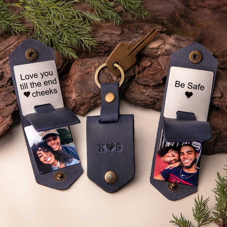 May include: Navy blue leather keychains with personalized photos and text. One keychain reads "Love you till the end cheeks" and another says "Be Safe". The center keychain has initials "K&hearts;S". Each keychain has a metal snap closure.
