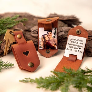 May include: Three brown leather keychains and cardholders. One keychain has a heart cutout. Two cardholders feature photos, one with a couple and the other with the text "Baby Shark, Doo doo doo I am obsessed with you! Xoxo, Your Tofu."