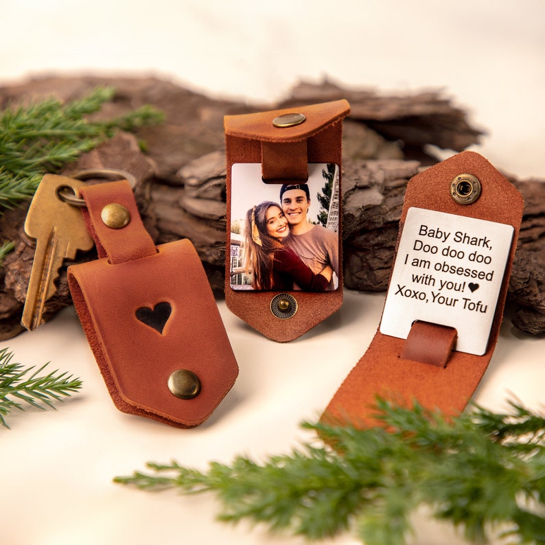 May include: Three brown leather keychains and cardholders. One keychain has a heart cutout. Two cardholders feature photos, one with a couple and the other with the text "Baby Shark, Doo doo doo I am obsessed with you! Xoxo, Your Tofu."