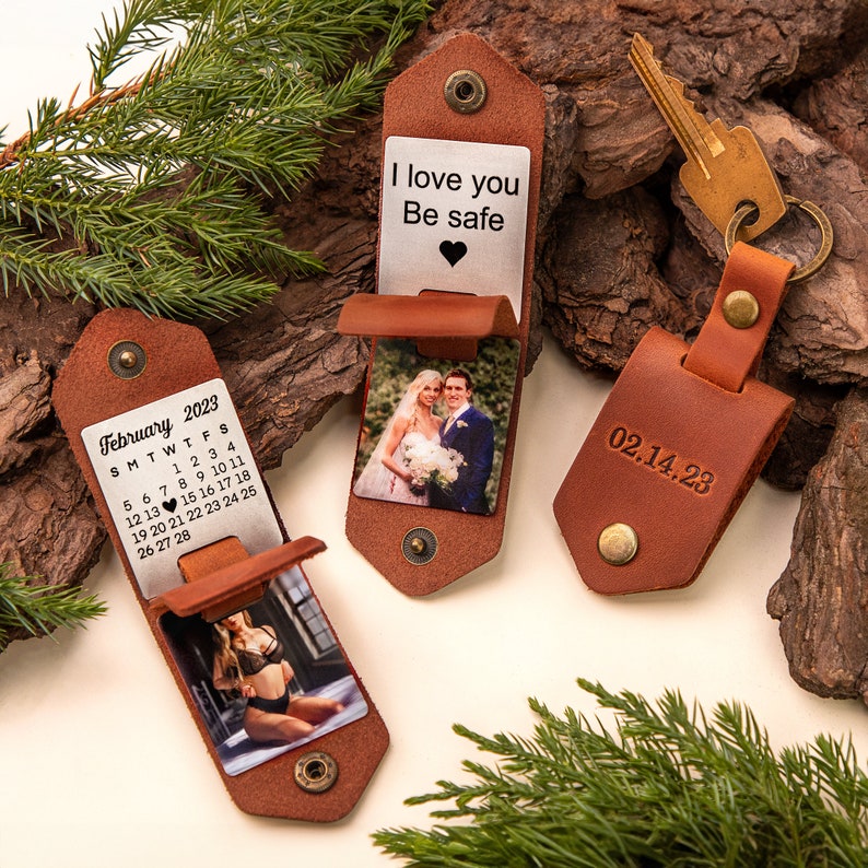 May include: Three brown leather keychains and holders. One keychain has the date 02.14.23 engraved. Two holders have metal inserts with photos and text: "I love you, Be safe" and a February 2023 calendar. The holders have snap closures.