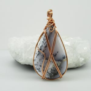 May include: A white ceramic mug with a black handle and the text "But First, Coffee" in a bold, black font. The mug is set against a neutral background, highlighting its simple design.