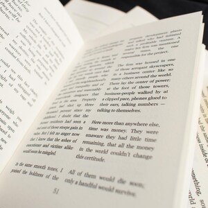 May include: An open book with printed text on cream-colored pages. Yellow-tinted sunglasses rest on the edge of the book. The book is slightly angled, with the text visible and in focus. The theme is literature.