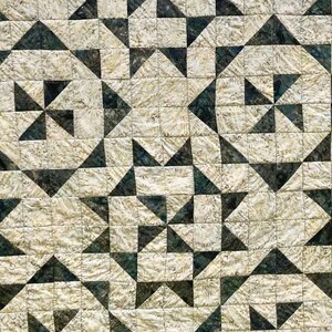 May include: A quilt with a geometric pattern of black and white triangles on a cream background.