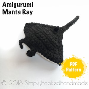 Może przedstawiać: Czarna, szydełkowa mantaraya amigurumi z białymi detalami. Mantaraya leży na białym tle. Tekst "PDF Pattern" znajduje się w żółtym kółku z białym obramowaniem.
