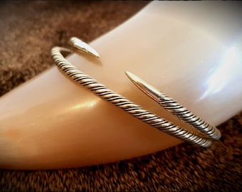 May include: A silver twisted wire bangle bracelet with two pointed ends.