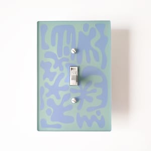 May include: Light blue abstract shapes on a light green background light switch cover plate. The switch is white and says "OFF".