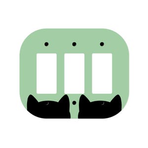 Puede incluir: Una placa de interruptor triple verde claro con tres recortes rectangulares para interruptores. La parte inferior de la placa tiene dos siluetas de gatos negros. La placa tiene tres puntos negros en la parte superior.