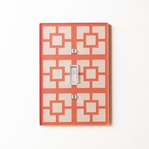 Puede incluir: Una tapa de interruptor de luz con un patrón geométrico en coral y blanco. El interruptor está etiquetado como "OFF".