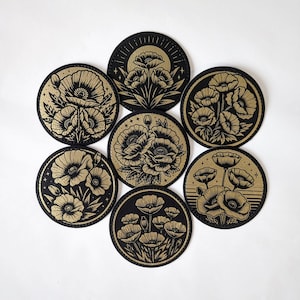 May include: Set of eight black and gold round stickers featuring a floral design with poppies. Each sticker has a different arrangement of poppies and leaves.