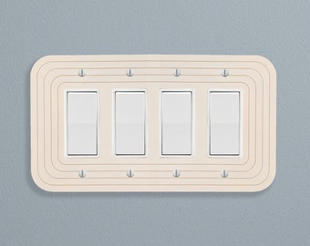 May include: A white light switch plate with four toggle switches. The plate has a decorative, concentric circle design.