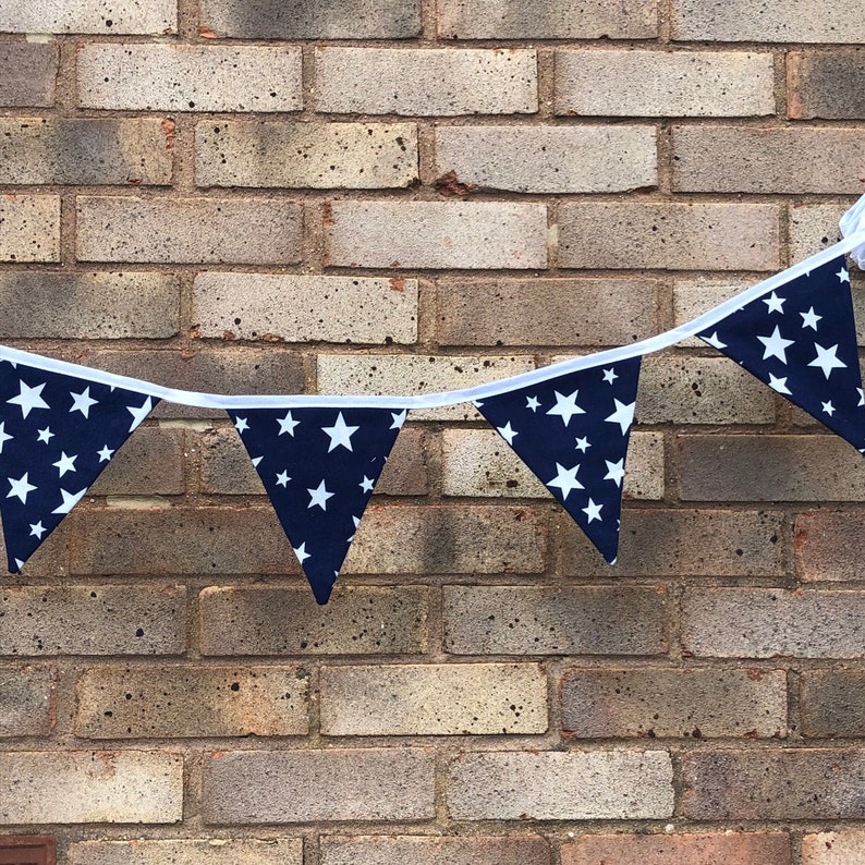 May include: A navy blue and white star patterned bunting with white trim hanging on a brick wall.