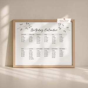May include: A framed birthday calendar with a light wood frame. The calendar is white with black text, listing names and dates for each month. Decorative leaf illustrations are at the top. The words "Birthday Calendar" are at the top.