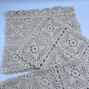 May include: Beige crochet doilies with a floral pattern. The doilies are square-shaped and feature a detailed openwork design. The crochet work is intricate, with a scalloped edge. The doilies are made of a soft, natural-looking yarn.