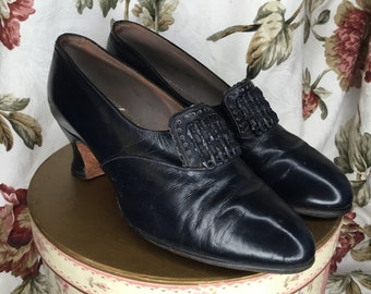 Zapatos antiguos de cuero azul oscuro de la década de 1920: tacones Luis XV, detalle de hebilla de imitación.