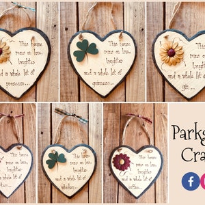 May include: Six heart-shaped slate signs with different floral and shamrock embellishments. Each sign has the text "This house runs on love, laughter, and a whole lot of..." followed by a different beverage, such as prosecco, gin, or Guinness. The signs are hung with twine and have a rustic, farmhouse aesthetic.