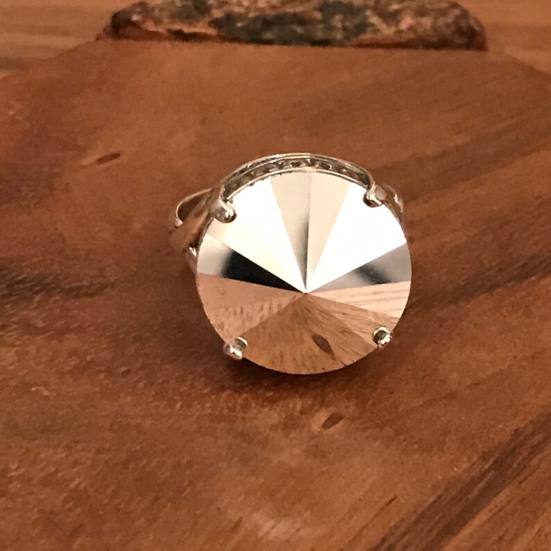 May include: A silver ring with a large, faceted, clear crystal stone.