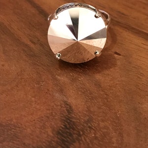 May include: A silver ring with a large, faceted, clear crystal stone.
