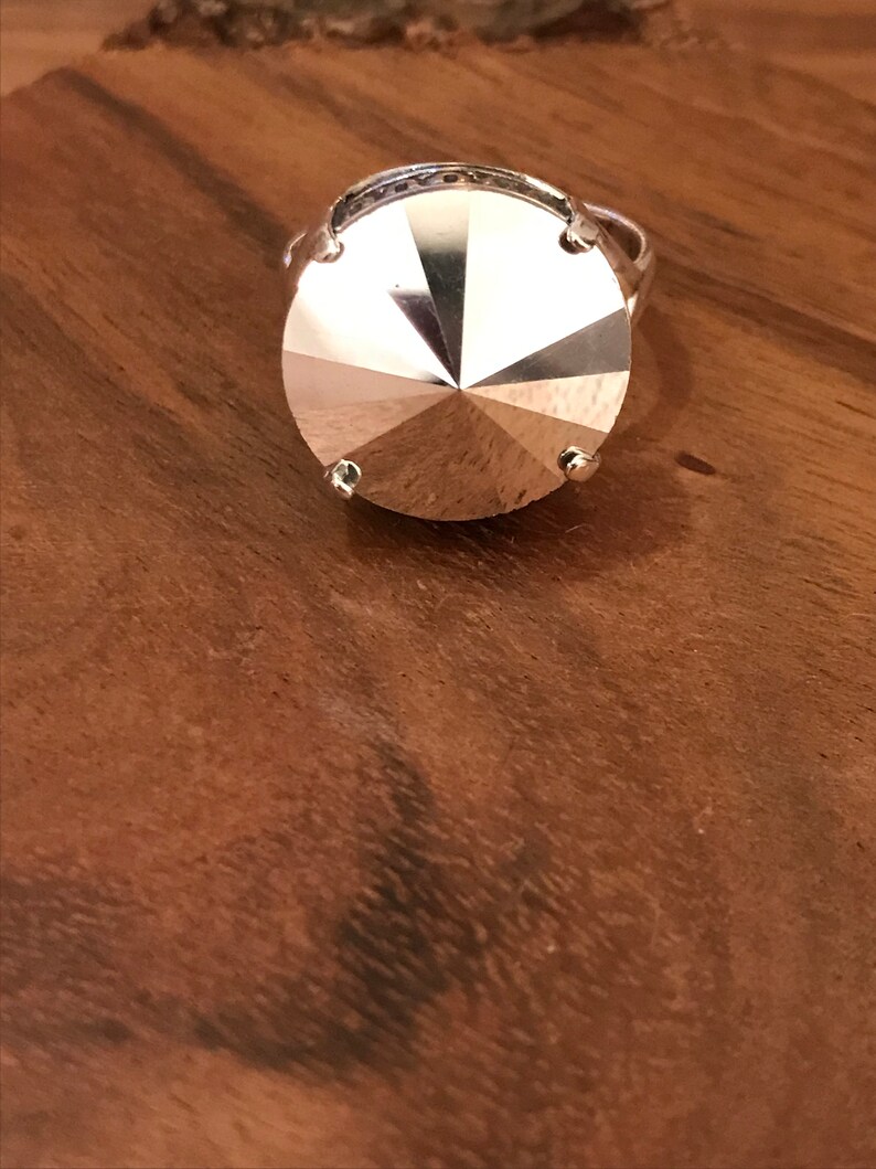 May include: A silver ring with a large, faceted, clear crystal stone.