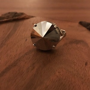 May include: A silver ring with a large, faceted, clear crystal stone.