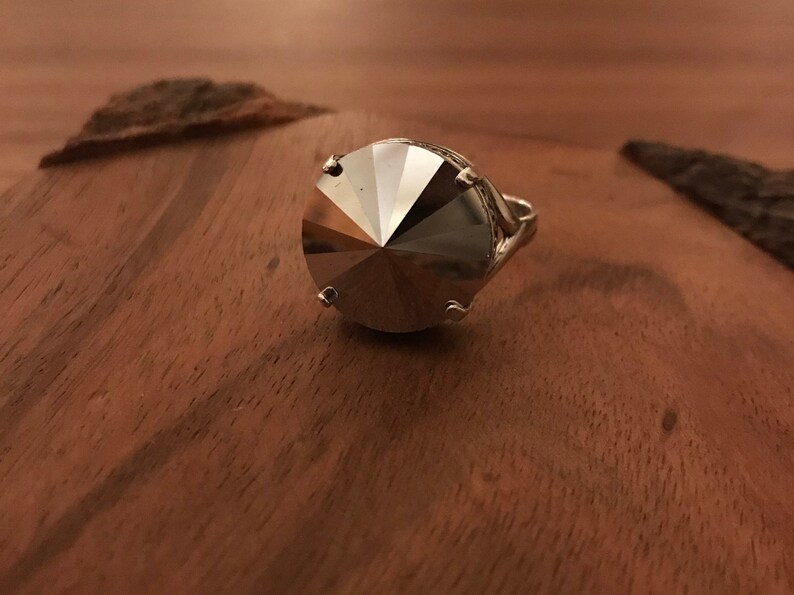 May include: A silver ring with a large, faceted, clear crystal stone.