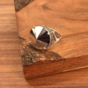 May include: A silver ring with a large, faceted, clear crystal stone.