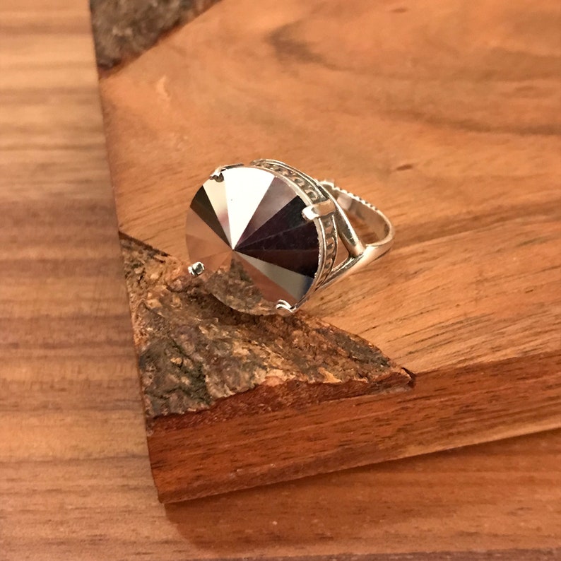 May include: A silver ring with a large, faceted, clear crystal stone.