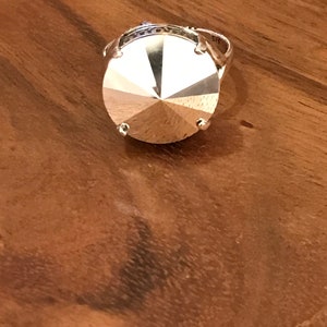 May include: A silver ring with a large, faceted, clear crystal stone.