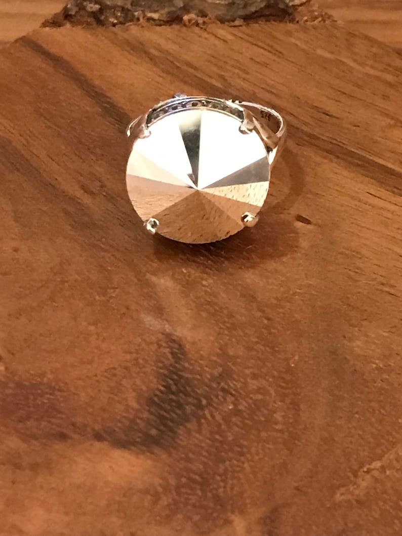 May include: A silver ring with a large, faceted, clear crystal stone.