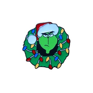 May include: A green Grinch character wearing a Santa hat and a wreath of Christmas lights. The Grinch has an angry expression. The wreath has red, blue, and yellow lights. The pin is on a white background.