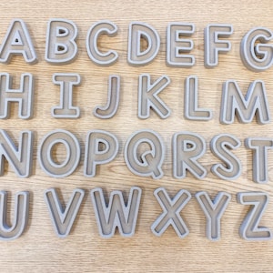 May include: A set of 26 gray plastic alphabet letter molds. The letters are arranged in alphabetical order from A to Z.