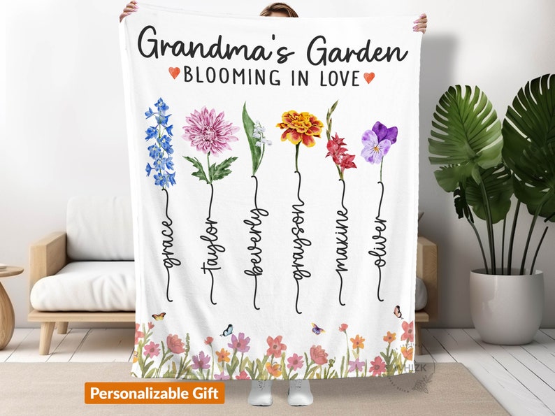 May include: White fleece blanket with a personalized floral design. The text reads "Grandma's Garden Blooming in Love" with a heart symbol on each side of the text.  The blanket features five different flowers with names written underneath each flower: Grace, Taylor, Beverly, Grayson, Maxine, and Oliver.