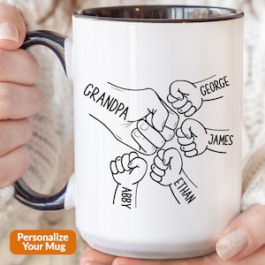 Peut inclure: Un mug en céramique blanche avec un intérieur et une anse bleu foncé, orné d'un dessin au trait noir représentant un grand check de poings entouré de quatre plus petits. Les noms Grandpa, George, James, Ethan et Abby sont inscrits.