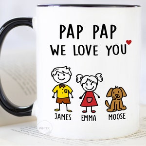 May include: White ceramic mug with a black handle. The mug has a black rim and says "Pap Pap We Love You" with a red heart. There are stick figure drawings of a boy, girl, and dog with the names "James", "Emma", and "Moose" underneath.