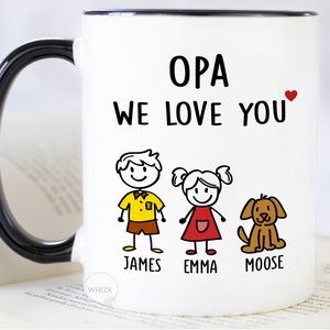 May include: White ceramic mug with a black handle. The mug has a red heart and the text "OPA WE LOVE YOU" in black. Below the text are stick figure drawings of a boy, girl, and dog with the names "JAMES", "EMMA", and "MOOSE" underneath.