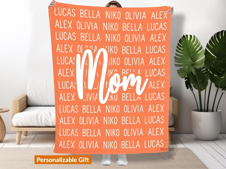 May include: A coral orange fleece blanket with the word "Mom" in white text. The blanket is personalized with a repeating pattern of names, including Lucas, Bella, Niko, Olivia, and Alex.