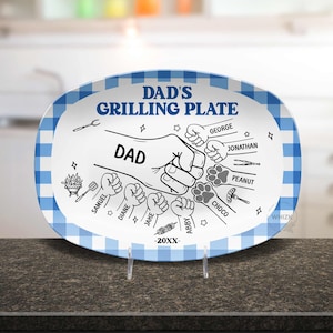 May include: An oval white serving plate with a blue and white checkered border. The center features black line art of a large fist bump labeled DAD, surrounded by smaller fists and paw prints with names, grilling icons, and the text DAD'S GRILLING PLATE -20XX-.
