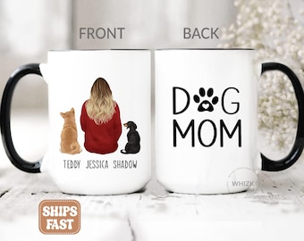 May include: A white ceramic mug with a black handle featuring a graphic of a person with long blonde hair in a red sweater sitting between a tan dog and a black dog, with the names Teddy, Jessica, and Shadow below. The back displays the text DOG MOM.
