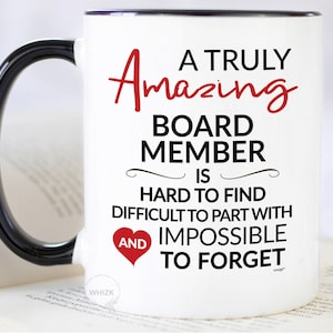 Peut inclure: Un mug en céramique blanche avec une anse et un bord noirs. Le texte indique : A TRULY AMAZING BOARD MEMBER IS HARD TO FIND DIFFICULT TO PART WITH AND IMPOSSIBLE TO FORGET. Le mot AMAZING est écrit en rouge et inclut un petit cœur rouge.