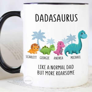 May include: A white ceramic mug with a black handle and rim. The front features the text DADASAURUS, a row of four colorful cartoon dinosaurs with the names SCARLETT, GEORGIE, ANDREA, and MICHAEL below them, and the text LIKE A NORMAL DAD BUT MORE ROARSOME.