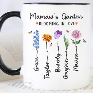 May include: White ceramic mug with a black handle. The mug has a floral design with the text "Mamaw's Garden Blooming in Love" and the names "Grace, Taylor, Beverly, Grayson, Maxine" written in a script font.