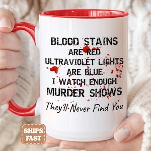 May include: A white ceramic mug with a bright red interior and handle. The mug features black text that reads: BLOOD STAINS ARE RED ULTRAVIOLET LIGHTS ARE BLUE. I WATCH ENOUGH MURDER SHOWS They'll-Never Find You, accented with red blood splatter.