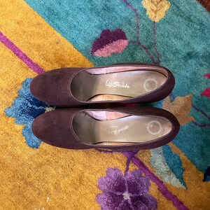 May include: A pair of brown suede heeled shoes with the brand name "Life Stride" printed on the insole.