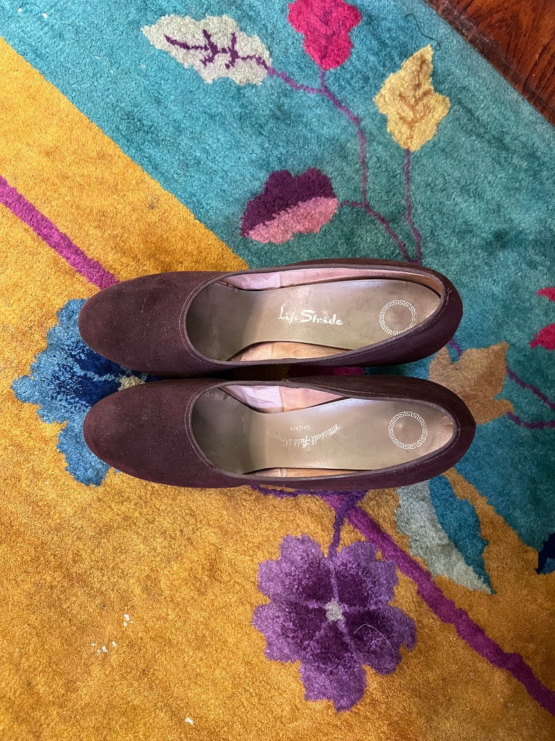 May include: A pair of brown suede heeled shoes with the brand name "Life Stride" printed on the insole.
