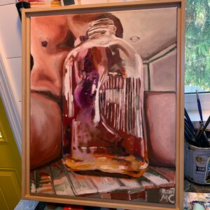 May include: A painting of a nude torso and a large glass jar filled with purple flowers. The jar is sitting on a table with a patterned tablecloth. The painting is framed in a light wood frame.