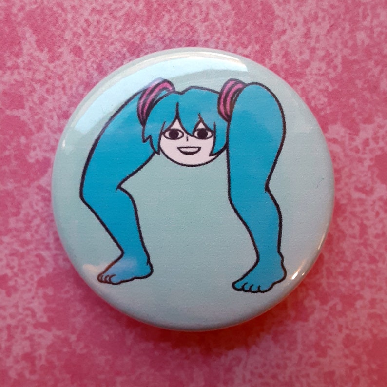 May include: A round, light blue button featuring a cartoon character with blue hair and legs. The character's hair is styled in pigtails with pink accents. The character's legs are bent, and the feet are visible at the bottom of the button.