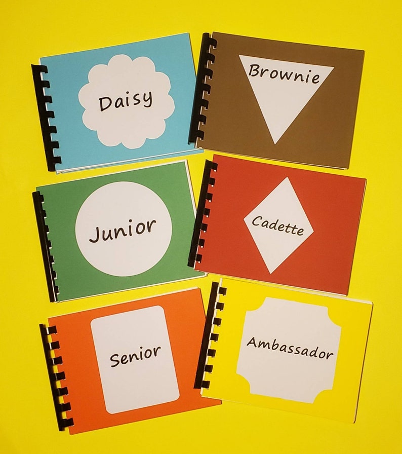 Puede incluir: Cinco peque&ntilde;os libros de espiral de colores diferentes con diferentes formas y nombres. Los libros son: Daisy, Brownie, Junior, Cadette y Ambassador.